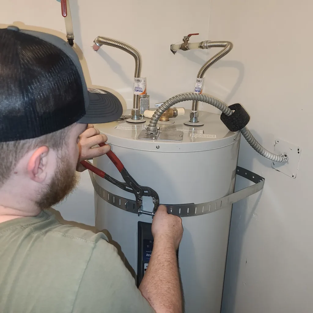 Technician securing a new electric water heater with seismic straps